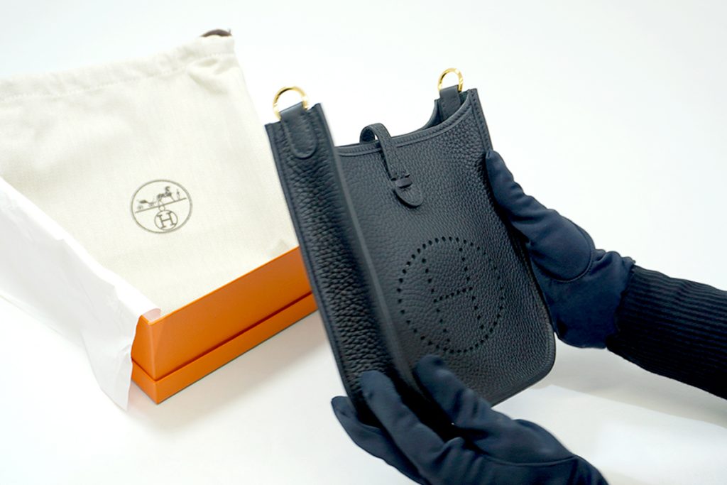 エルメスのブラックのエヴリンを手袋を着用したスタッフが検品する様子